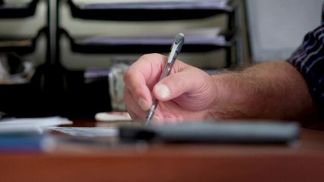 An adult man writes with a pen. Hands are stained with ink. slow motion