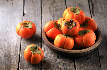 Still life with fresh persimmons on a wooden table.