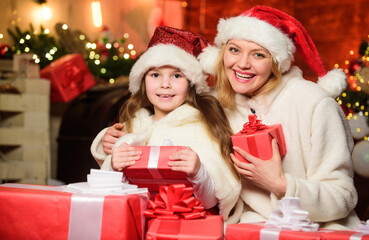 Fototapeta na wymiar joy and cheer. Happy family celebrate new year. merry christmas. mother and daughter love holidays. small child girl with mom in santa hat. xmas gift boxes. Open present. Winter shopping sales