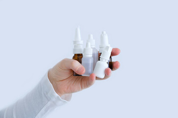 Bottles with nose drops in  hand of a Caucasian woman close up. White background.