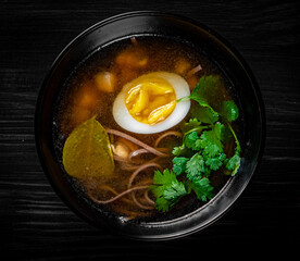 Japanese ramen soup with tofu and egg on black wooden table background