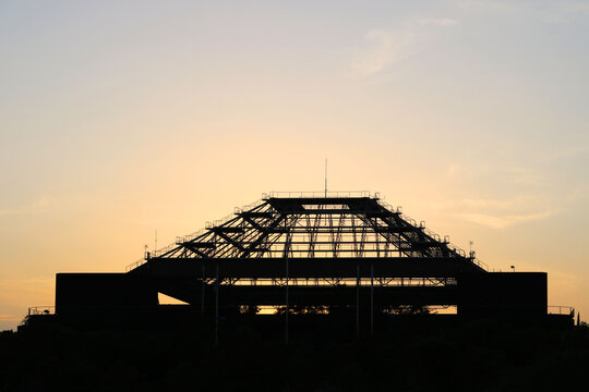silhouette of a modern metal structure with scaffolding at sunset in the city - beautiful industrial wallpaper - Powered by Adobe