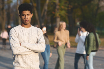 Depressed black guy standing apart from laughing students