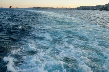 Bubbling blue waves of traces of tourist cruise ships passing on the Bosporus. Water trail foaming behind a passenger ferry boat in Bosphorus, Istanbul, Turkey.