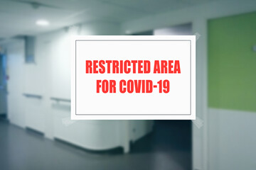 Sign on the door of a hospital corridor indicating an access area reserved for patients with covid-19