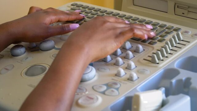 Close up of hands of african american female doctor working on ultrasound device