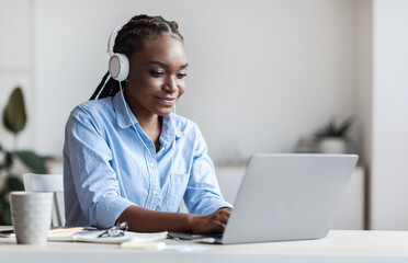 Millennial Black Female Employee Working With Laptop And Listening Music In Office