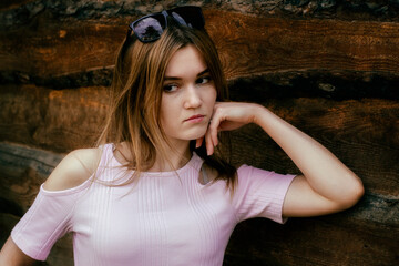 Fototapeta premium Portrait of a beautiful girl with glasses on a wooden background.