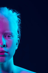 Feeling. Close up portrait of beautiful albino girl on dark background in neon light. Blonde female...