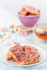 Homemade cookies with colored sugar with tea on a light wooden background. The concept of breakfast.