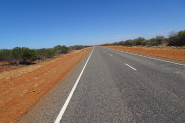 Driving through the red Australian outback on straight roads for miles