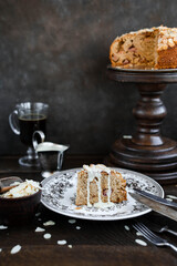 A slice of apple pie in almond flakes with a creamy sauce. Still life with dessert and vintage dishes. Dark shades.