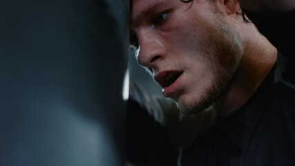 Tired fighter having break on ring. Sportsman leaning on bag in sport club