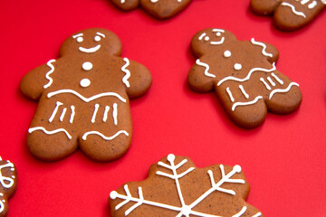 Tasty homemade Christmas gingerbread cookies of various shapes with sugar glaze on a bright festive red background. Merry Christmas card. Concept of celebrating new year. Christmas mood