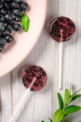 Homemade lollipops made from natural dehydrated bilberry on a white wooden background. Healthy vegan vegetarian food with no sweets.