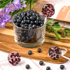Homemade lollipops made from natural dehydrated bilberry on a white wooden background. Healthy vegan vegetarian food with no sweets.