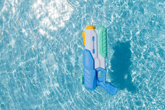 A child's blue water gun floats in the pool. A toy for playing in the pool or on the beach