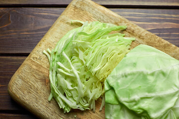 Shredded cabbage salad on wooden cutting board and plate over wooden background.