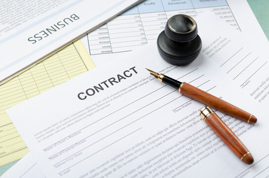 Closeup of contract documents, business newpaper, pen and stamp on the desk