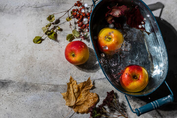 Apples and autumn colorful leaves on a gray background with raindrops.
