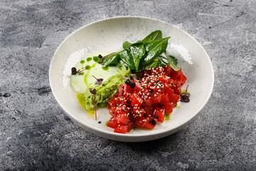 Exquisite fish tartare raw tuna fillet with greens close up on a white plate