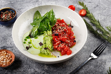 Exquisite fish tartare raw tuna fillet with greens close up on a white plate