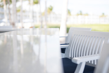 Long elegant simple white stone benchtop bar against bright white background with line of bar stools chairs seats 
