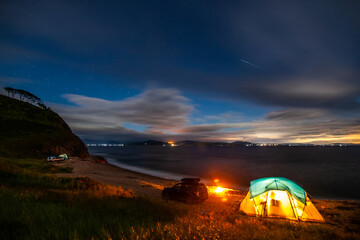 Naklejka na ściany i meble Tent camping at the sea coast in the night