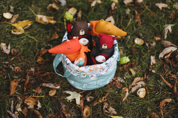 Cute little toys sit in a basket in the autumn garden. Childhood, baby, holiday, people, hobby, emotions concepts