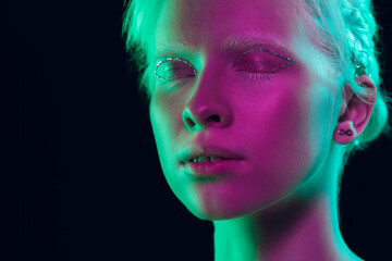 Sleepy. Close up portrait of beautiful albino girl on dark background in neon light. Blonde female model with dreamlike make-up and well-kept skin. Concept of beauty, cosmetics, style, fashion.