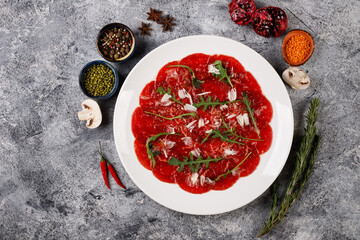 white dish with beef carpaccio with arugula