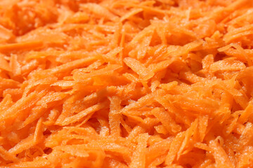 Carrots, grated on a large grater. Food orange background.