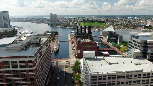 Aerial dolly shot, view of Baltimore Inner Harbor, Maryland, Patapsco River and Chesapeake Bay, Federal Hill in distance, busy urban USA city during summer