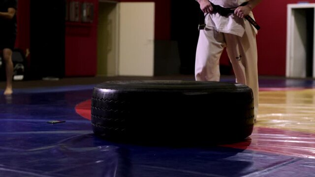 Sportsman in traditional kimono does tire jumps in gym