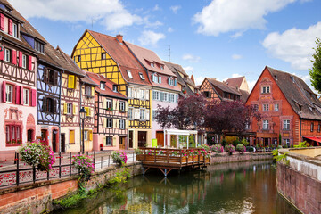 Fototapeta na wymiar Picturesque view on Colmar street. Colourful architecture, canal and blue sky. Alsace, France