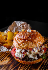Traditional beef burger with vegetables on dark background