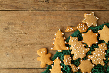 christmas gingerbread cookies lie in a green string bag on a light brown wooden background