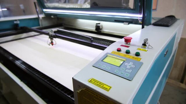 Employee presses keys on plotter control panel in typography