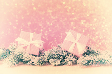 Gift boxes with frosty fir tree branches over pink background. Vintage style edited photo