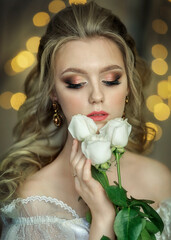 Bride with a bouquet of roses in a white dress on a yellow bokeh background.
