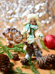 handmade Christmas doll man in a fur coat on the Christmas tree, on the background of a gift and cones. New Year's atmosphere.