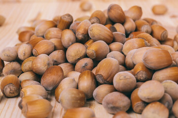 Pile of nuts. Hazelnuts. Whole nuts. Corylus avellana. Macro photo, close up, on wooden table.