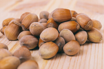 Pile of nuts. Hazelnuts. Whole nuts. Corylus avellana. Macro photo, close up, on wooden table.