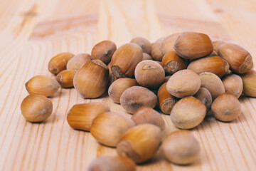 Pile of nuts. Hazelnuts. Whole nuts. Corylus avellana. Macro photo, close up, on wooden table.