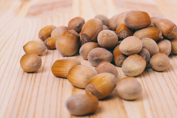 Pile of nuts. Hazelnuts. Whole nuts. Corylus avellana. Macro photo, close up, on wooden table.