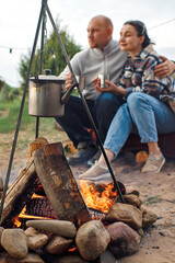 A guy and a girl are warming themselves by the fire.
