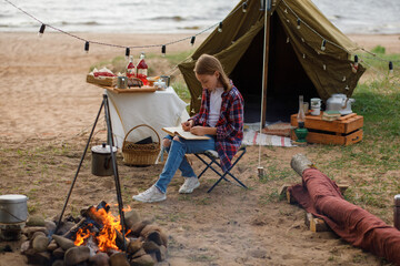 A girl in a plaid shirt and blue jeans is reading a book.
