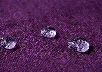 Water drops on purple fabric.
