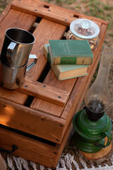 Mugs and books on a wooden box next to a lamp.