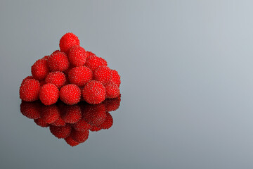 A pile of fresh raspberries with a reflection on a gray background.